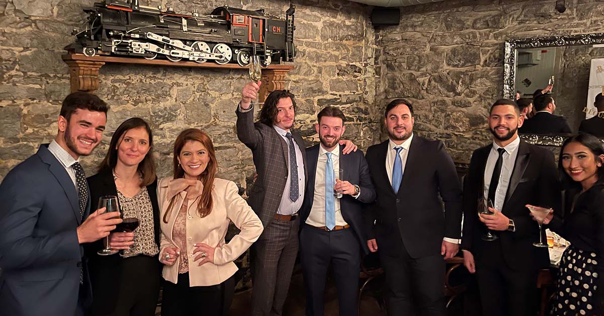 a smiling group of people in business attire smile and raise their glasses