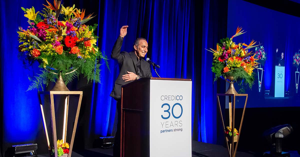 Antoine Nohra, founder and chairman of Credico, smiles and gestures indicating a tall height at Credico's November 2021 awards ceremony in Las Vegas.