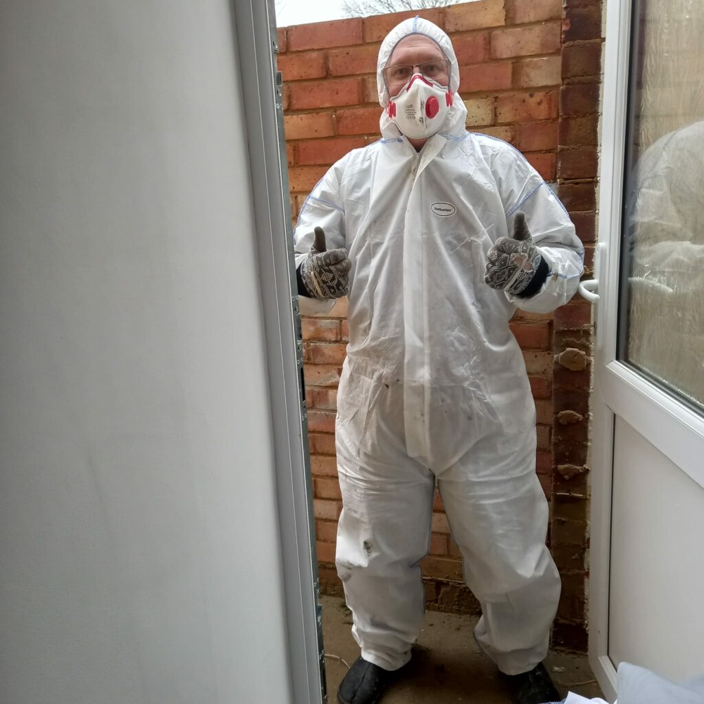 Scott Watson wearing a hooded coverall and particulate mask to remodel his home