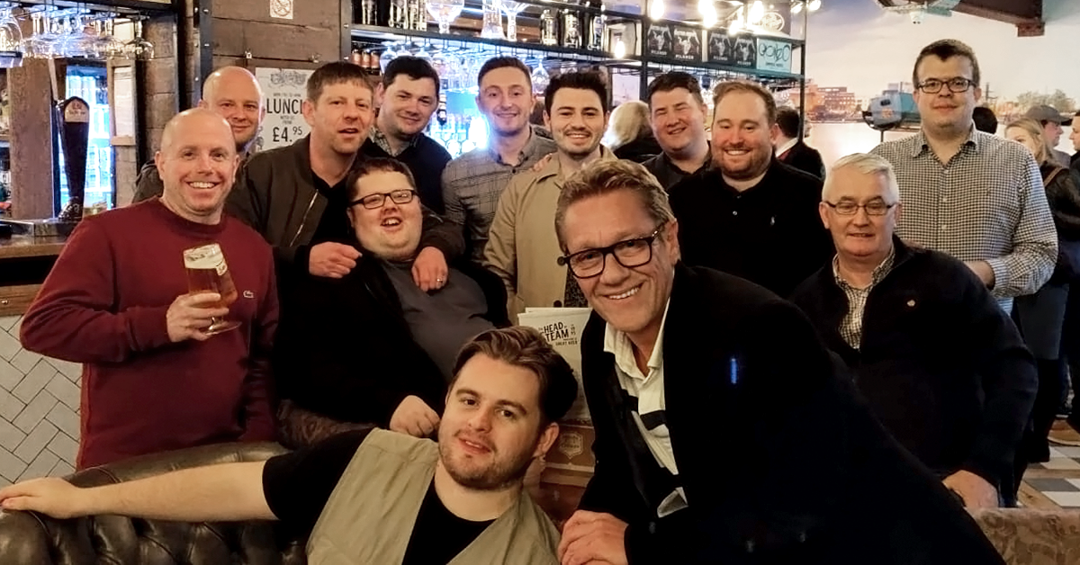 John Dougan poses at a celebratory event with a dozen team members