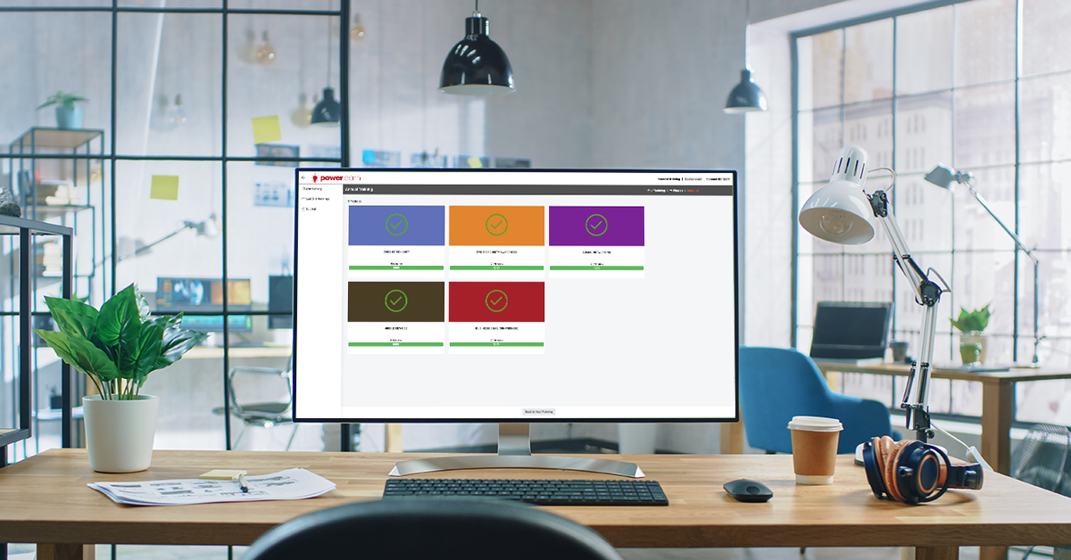 A computer screen in an office displaying a PowerLearn training interface indicating 100% completion of five modules