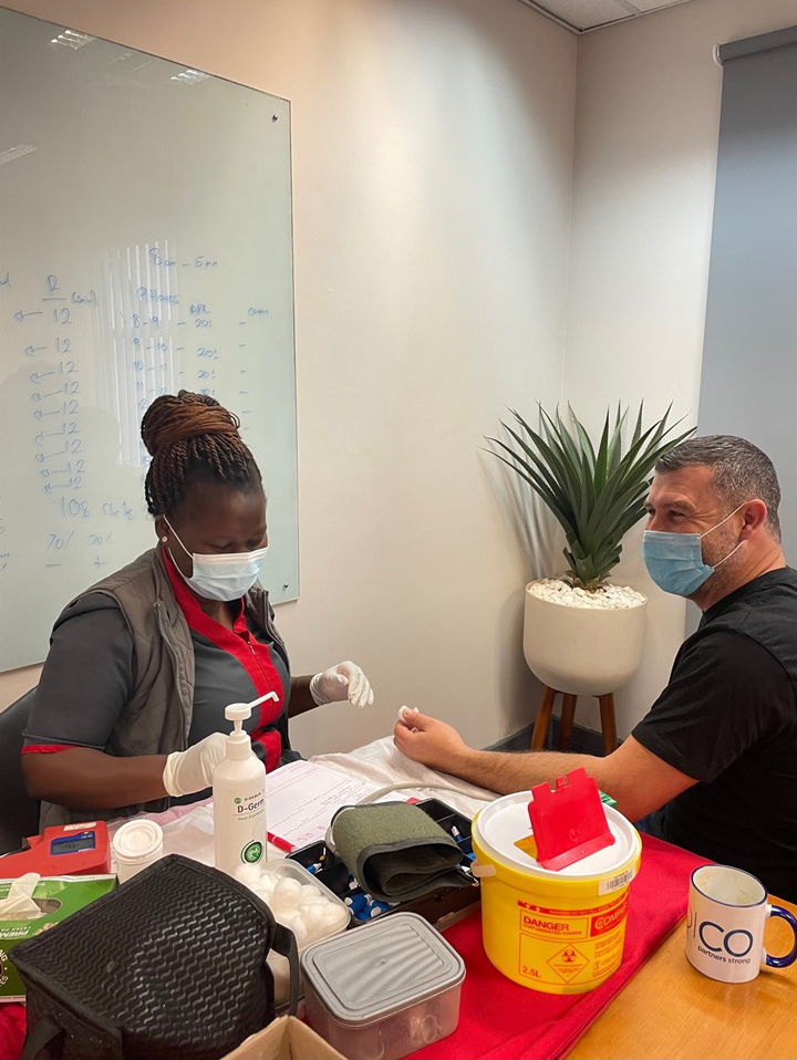 A Credico South Africa staff member sitting at a table with a SANBS worker to prepare for a blood donation