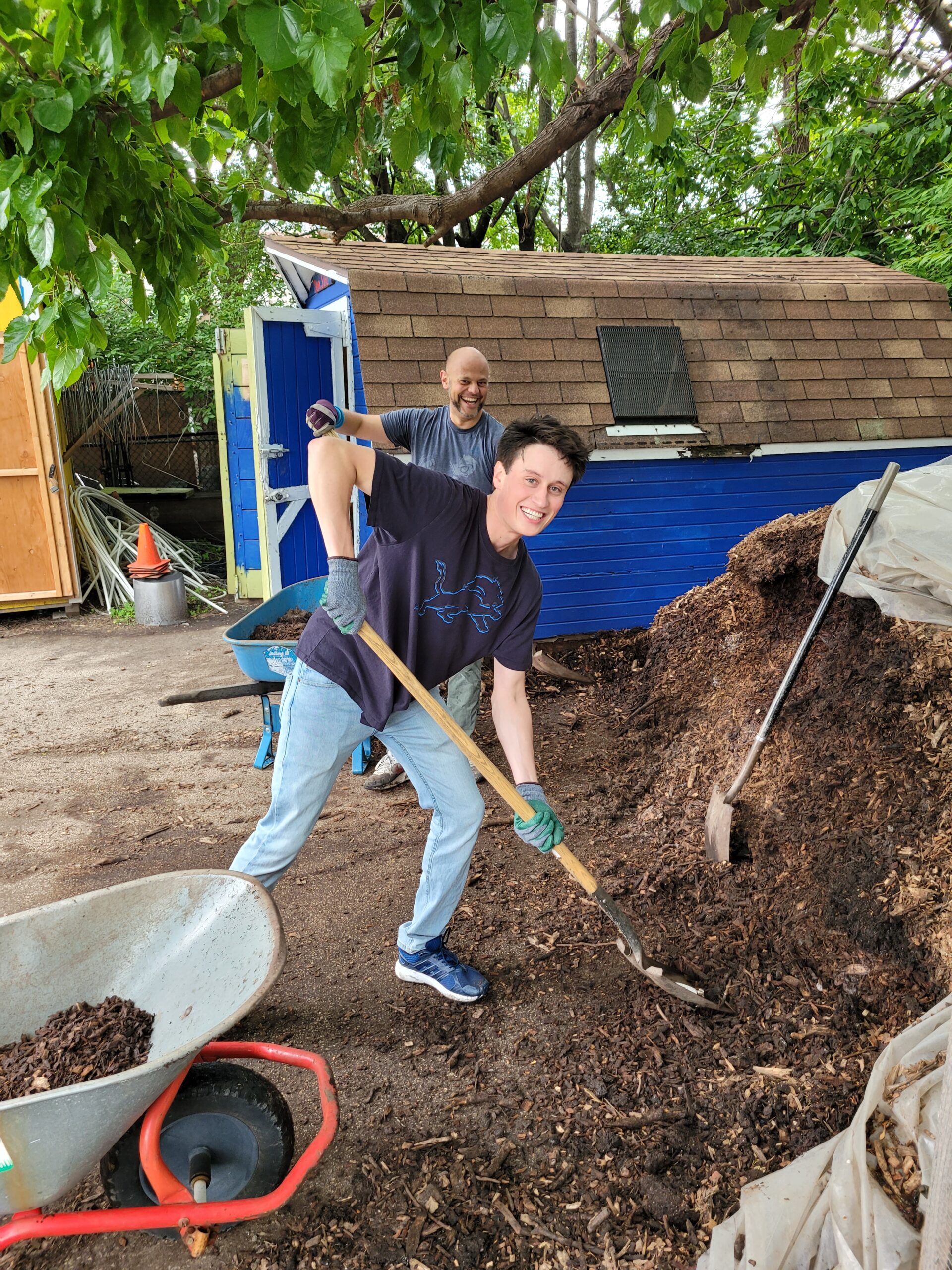 Neil Pandey and Brennan Delaney shovel mulch at Chicago Lights Urban Farm