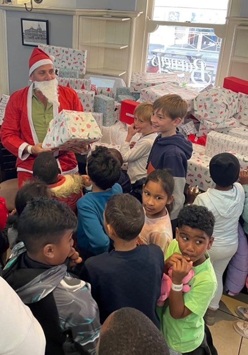 Children gather around "Santa" as he hands out gifts at Credico South Africa's 2022 Christmas in July event