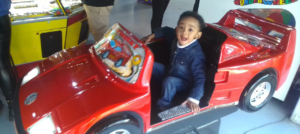 a happy child of a Credico SA staff member rides a toy racecar at the Gold Reef City Theme Park during the 2022 Christmas in July outing