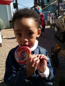 A child of Credico SA parents happily eats a large spiral lollipop at the Gold Reef City Theme Park during the 2022 Christmas in July outing