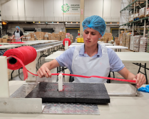 Brennan Delaney, Credico USA Commissions Analyst, measures out mesh rope to tie into bags for apples at a volunteer event at the Greater Chicago Food Depository.