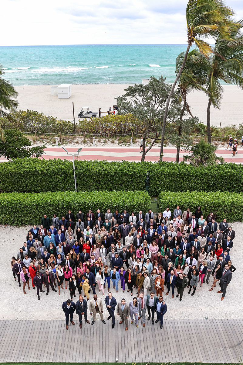 An aerial view of a large crowd of attendees wearing business suits on the boardwalk in front of the Fontainebleau Hotel in Miami the day before the 2023 Awards Gala