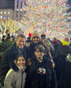 Jeremy Klarner and his family pose for a photo in front of a large outdoor Christmas tree in winter