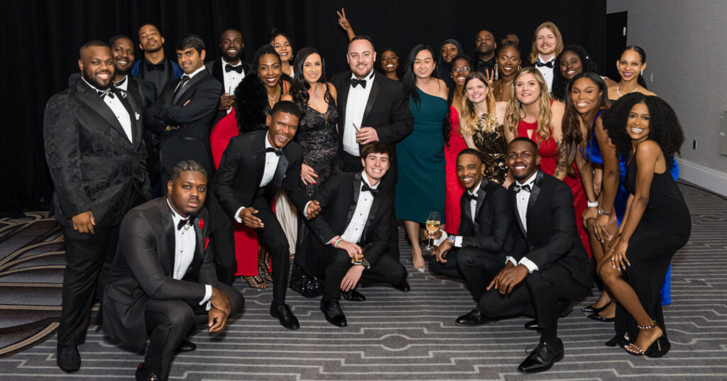 A group of attendees dressed in glittering formalwear pose for a photo during the January 2023 North American Awards Gala in Miami, Florida