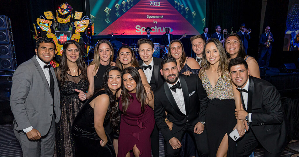 A group of attendees dressed in glittering formalwear pose for a photo during the January 2023 North American Awards Gala in Miami, Florida