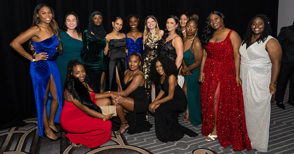 A group of attendees dressed in glittering formalwear pose for a photo during the January 2023 North American Awards Gala in Miami, Florida