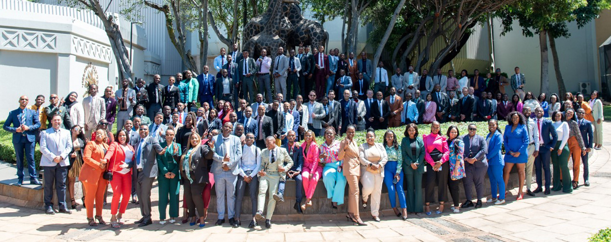 Representing their companies in stylish business attire, the entire group of attendees at Credico South Africa's 2023 Owners Conference Meeting pose outside of a statue of giraffes at Sun City Resort in March 2023