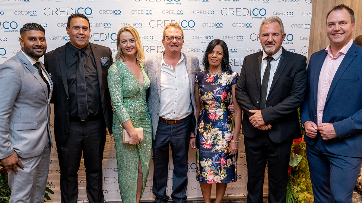 A group of seven guests pose for a group photo in front of a Credico-branded backdrop at Credico South Africa's 2023 Awards Gala at Sun City Resort