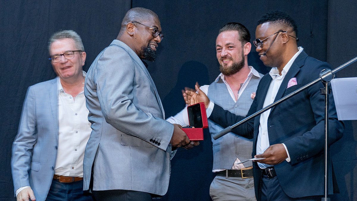 Kevin de Souza, Grant Sherwood, and Peter van den Berg congratulate Patrick Maloba as he accepts his award at Credico South Africa's 2023 Awards Gala at Sun City Resort
