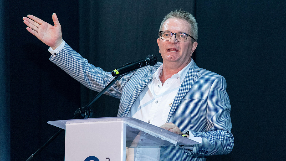 Peter van den Berg addresses the audience with a sweeping gesture on stage at Credico South Africa's 2023 Awards Gala at Sun City Resort