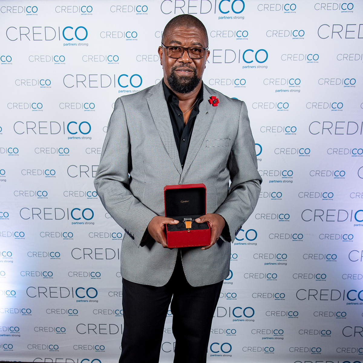 Patrick Maloba poses with his well-earned reward of a designer watch in front of a Credico-branded backdrop at Credico South Africa's 2023 Awards Gala at Sun City Resort.