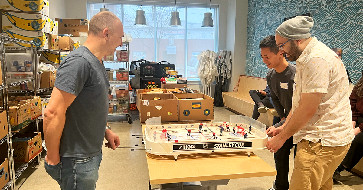Volunteers from Credico (USA) LLC's Legal and Onboarding departments play foosball with a Nourishing Hope staff member while on a break from their volunteer day at the food pantry.