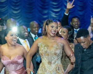 Kagiso Maswanganye stands from her seat amid a group of cheering supporters to accept an award during the South Africa Awards Gala in March 2025