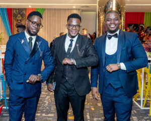 Three business owners in suits hold out their arms as if checking their watches at the South Africa Awards Gala in March 2025