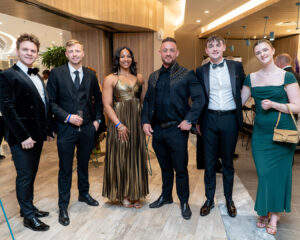 A smiling group of attendees, including National and Regional Consultants, poses for a photo in their gala finery before the South Africa Awards Gala in March 2025
