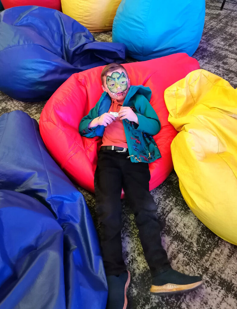 A child of a Credico SA employee relaxes in his face paint on a pile of colorful bean bag chairs at Credico South Africa's 2025 Christmas in July